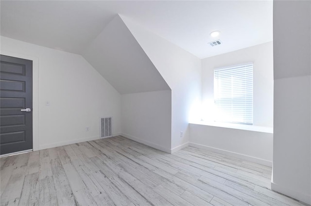 additional living space with light hardwood / wood-style flooring and vaulted ceiling