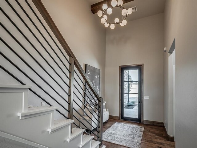 foyer entrance featuring baseboards, a chandelier, stairway, a high ceiling, and wood finished floors