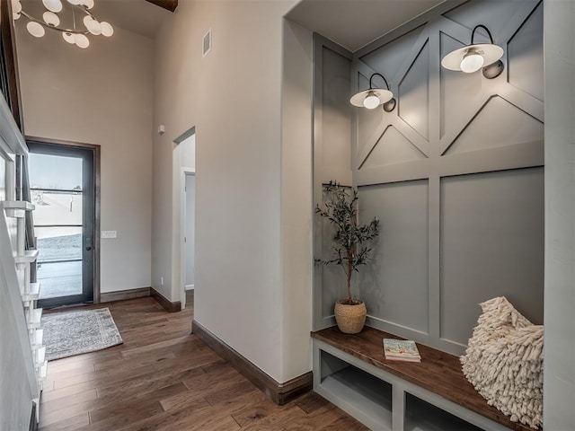 entrance foyer featuring visible vents, wood finished floors, an inviting chandelier, baseboards, and a towering ceiling