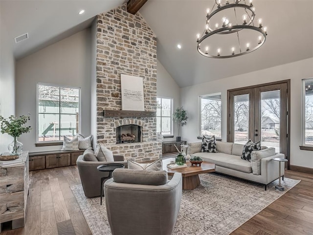 living room with french doors, a fireplace, visible vents, and light wood finished floors