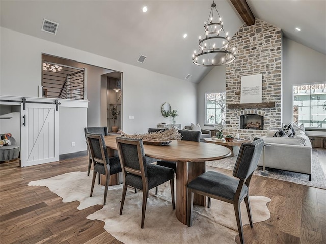 dining area with wood finished floors, visible vents, high vaulted ceiling, beam ceiling, and a brick fireplace