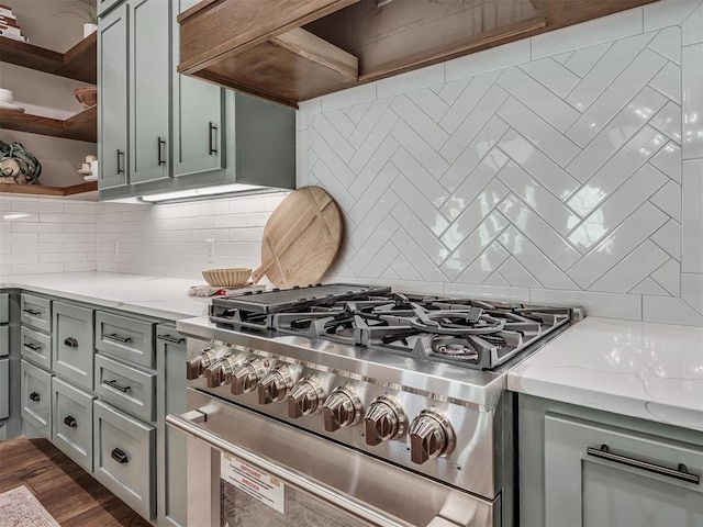 kitchen with gray cabinets, open shelves, light stone counters, tasteful backsplash, and stainless steel stove