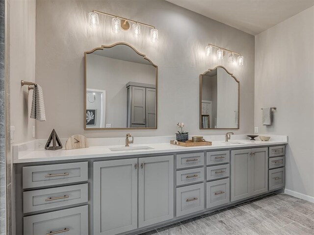 bathroom with a sink, baseboards, and double vanity