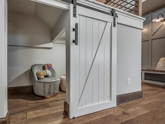 room details with a barn door, wood finished floors, and baseboards