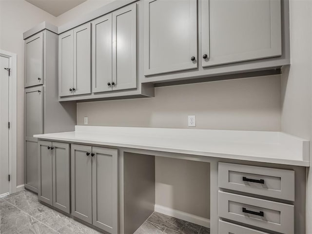 kitchen with gray cabinetry, built in study area, and light countertops