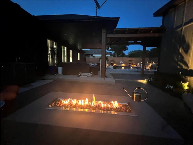 patio at night featuring a swimming pool and an outdoor fire pit