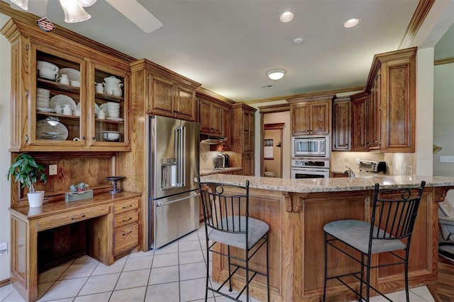 kitchen with kitchen peninsula, light stone countertops, stainless steel appliances, and decorative backsplash