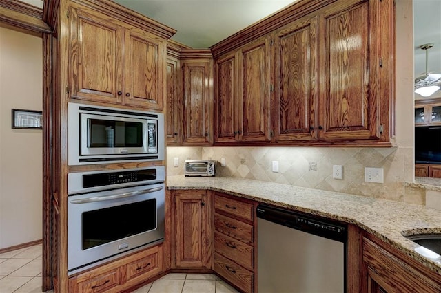 kitchen with light stone countertops, light tile patterned floors, stainless steel appliances, and decorative backsplash