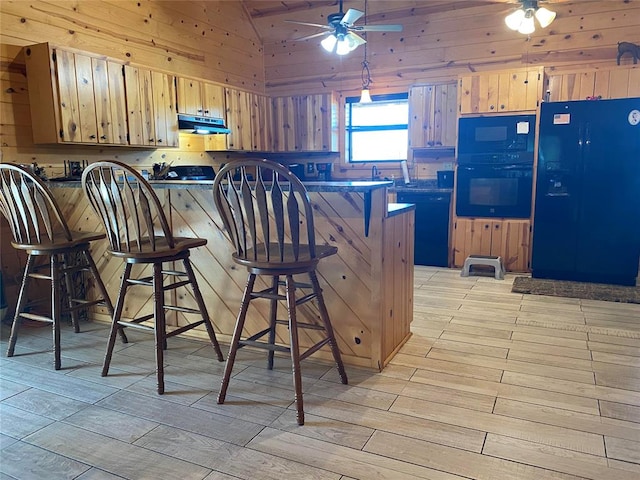 kitchen with a kitchen breakfast bar, light wood-type flooring, wooden walls, black appliances, and lofted ceiling