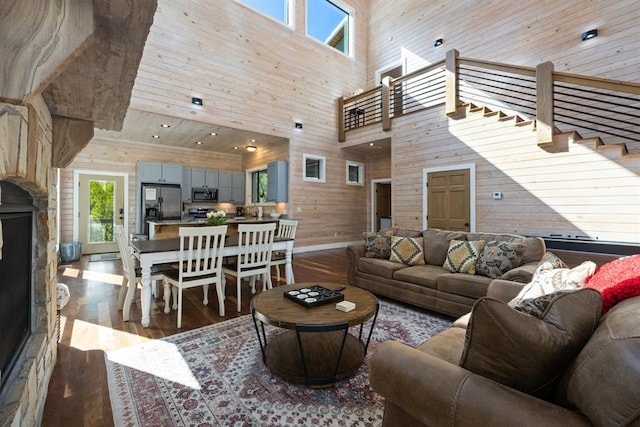 living room featuring a high ceiling, dark wood-type flooring, and wooden walls