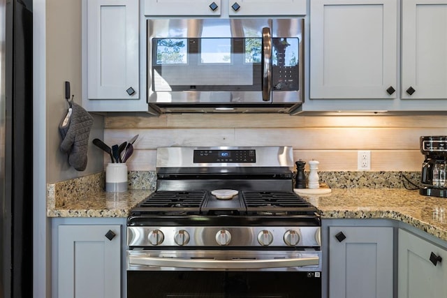 kitchen with white cabinets, appliances with stainless steel finishes, and light stone counters