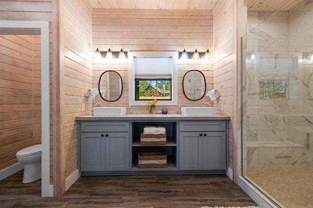 bathroom with vanity, wood-type flooring, toilet, a shower with shower door, and wood walls