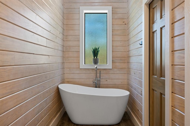 bathroom with a bathtub and wood walls