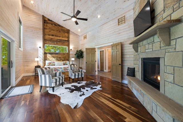 living room with high vaulted ceiling, a stone fireplace, wooden walls, dark hardwood / wood-style floors, and ceiling fan