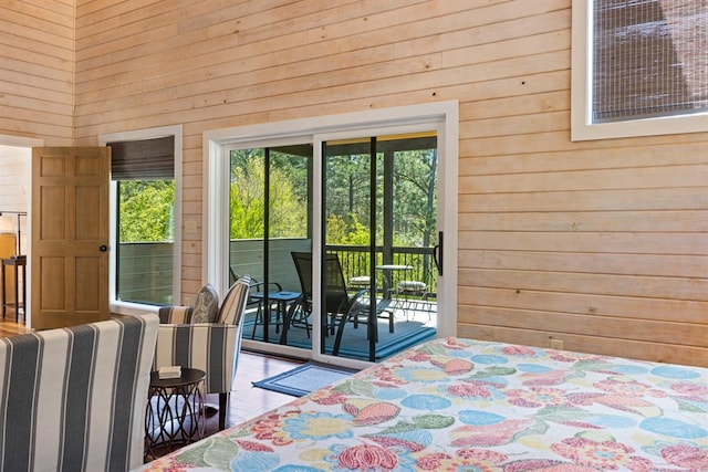 unfurnished bedroom featuring wooden walls, wood-type flooring, and access to outside