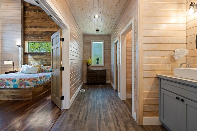 interior space featuring wood walls, vanity, wood-type flooring, and wooden ceiling