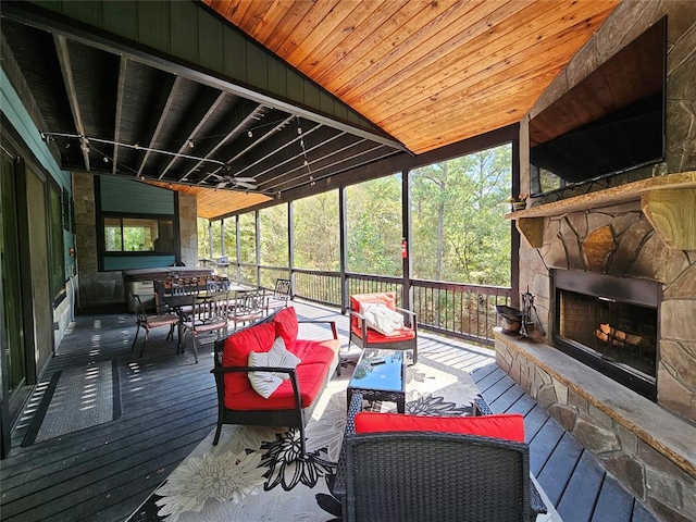 sunroom featuring an outdoor stone fireplace, wooden ceiling, and vaulted ceiling