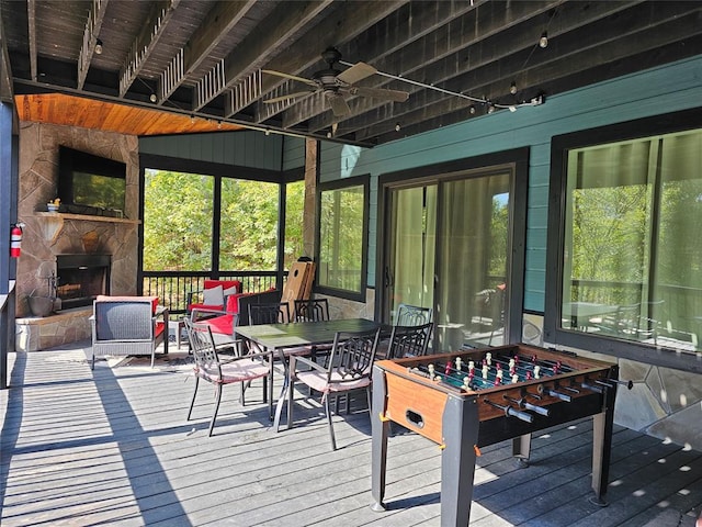 sunroom with ceiling fan and an outdoor stone fireplace