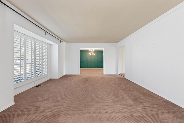 carpeted empty room featuring a chandelier and ornamental molding