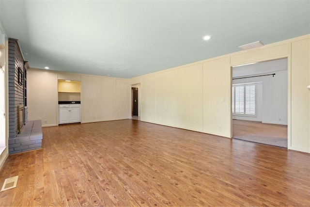 unfurnished living room with hardwood / wood-style flooring and a brick fireplace