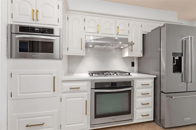 kitchen featuring decorative backsplash, light tile patterned floors, range hood, appliances with stainless steel finishes, and white cabinetry