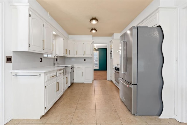 kitchen featuring sink, stainless steel appliances, tasteful backsplash, white cabinets, and light tile patterned flooring