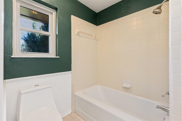 bathroom featuring tile patterned floors, tiled shower / bath combo, and toilet