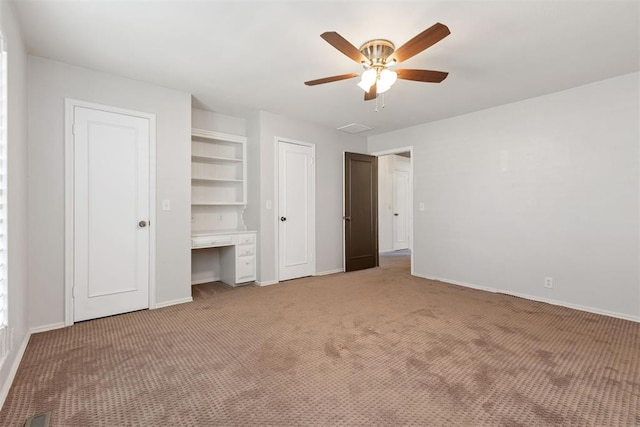 unfurnished bedroom with carpet, built in desk, and ceiling fan