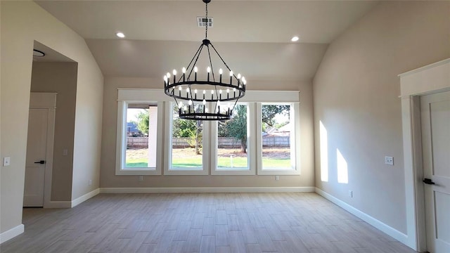 unfurnished dining area featuring plenty of natural light, light hardwood / wood-style floors, lofted ceiling, and a chandelier