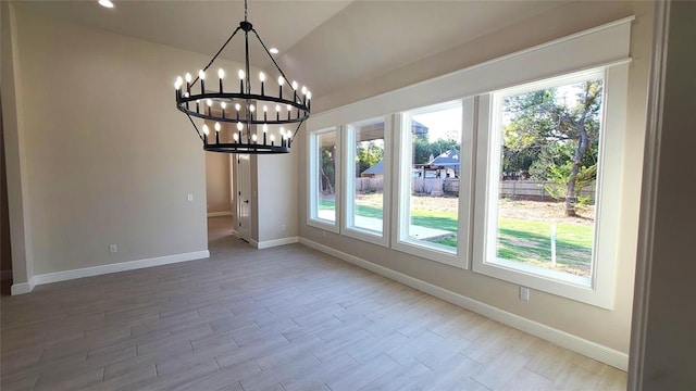 unfurnished dining area featuring hardwood / wood-style floors, lofted ceiling, and a notable chandelier