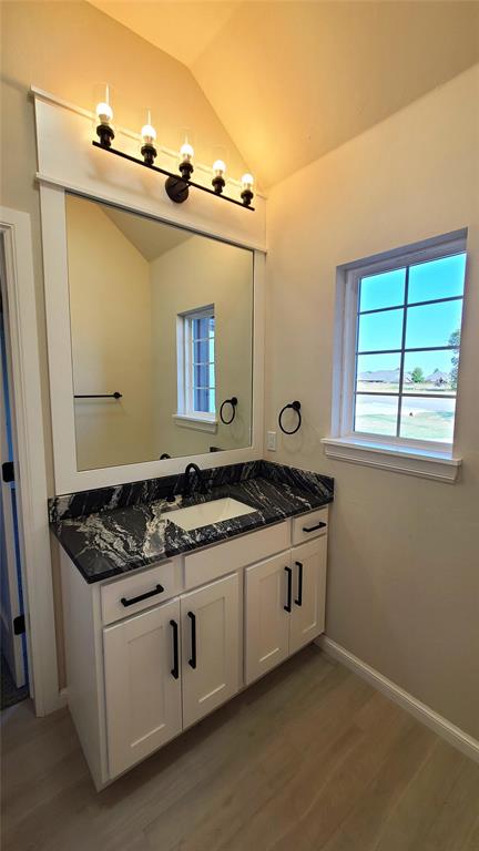 1308 W Harvard Way, Mustang, OK 73064 - bathroom featuring vanity, lofted ceiling, wood finished floors, and baseboards