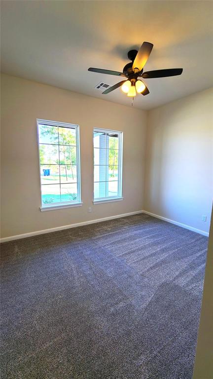 unfurnished room featuring ceiling fan and dark carpet