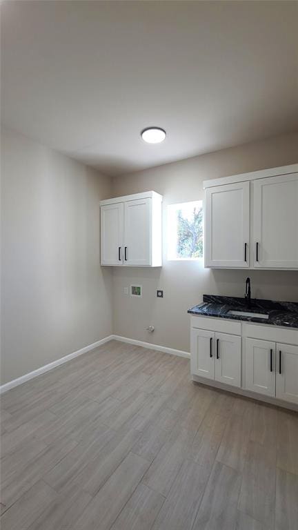 washroom with cabinets, hookup for a washing machine, light hardwood / wood-style floors, and sink