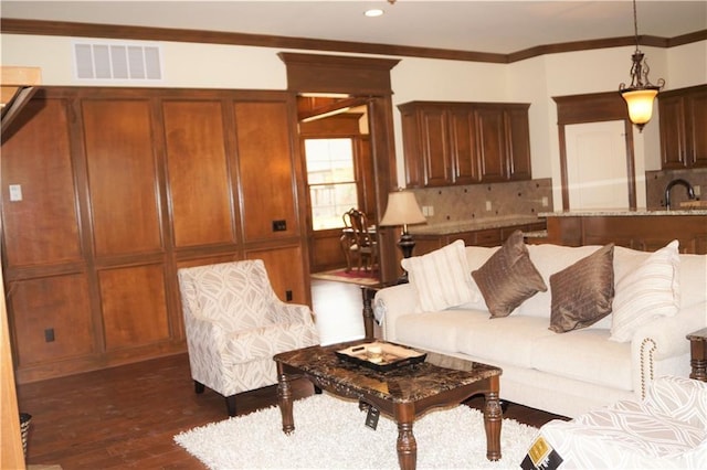 living room with dark hardwood / wood-style flooring, ornamental molding, and sink