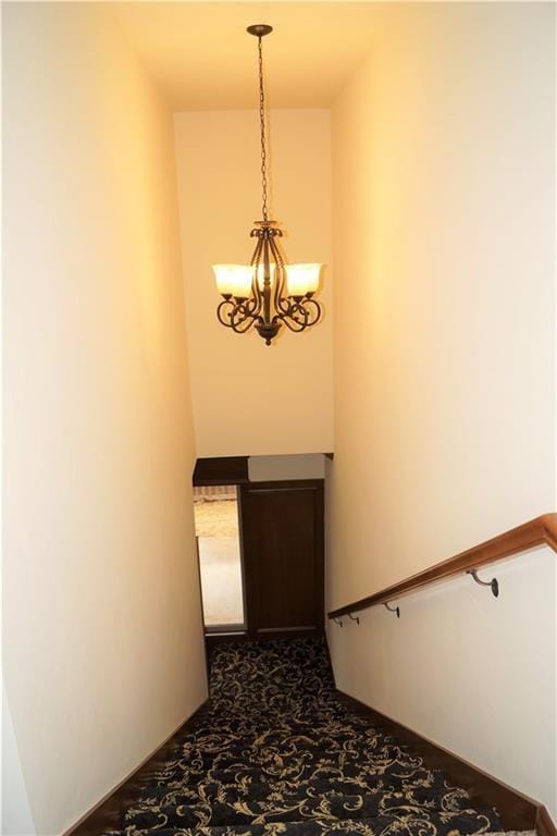 stairway with carpet floors and a chandelier