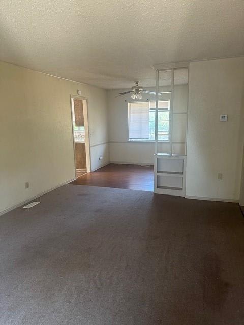 carpeted empty room with ceiling fan and a textured ceiling