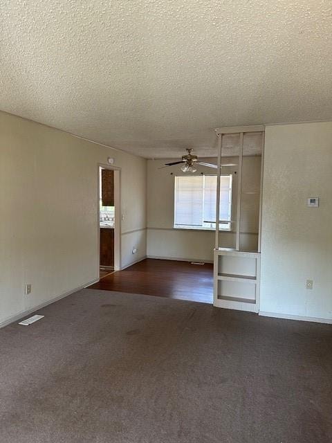 empty room with ceiling fan, dark carpet, and a textured ceiling