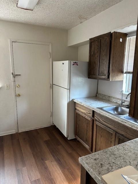 kitchen with dark hardwood / wood-style floors, white refrigerator, sink, and a textured ceiling