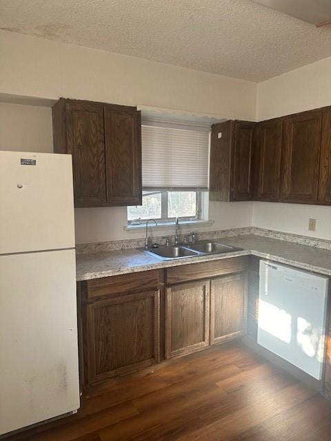 kitchen with dark brown cabinetry, sink, dark hardwood / wood-style flooring, a textured ceiling, and white appliances