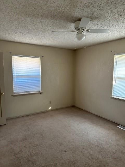 carpeted spare room with ceiling fan and a textured ceiling