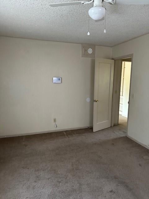 empty room featuring ceiling fan, a textured ceiling, and light carpet