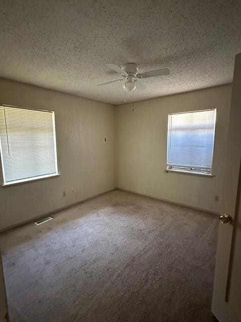 unfurnished room featuring a textured ceiling, carpet floors, and ceiling fan