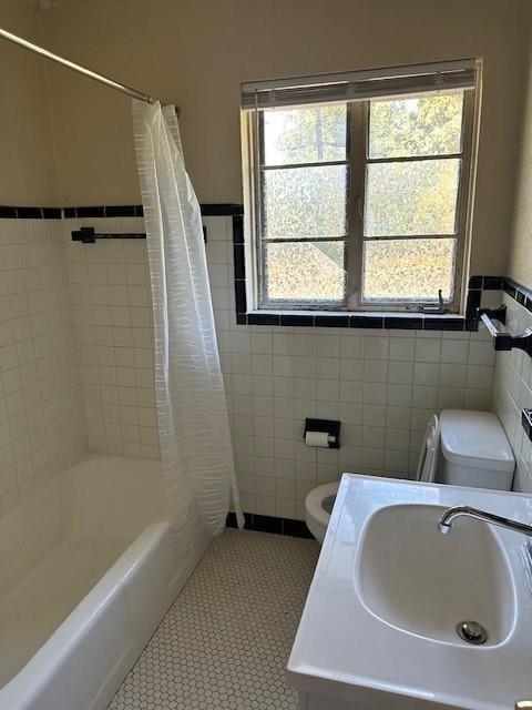 full bathroom featuring tile patterned flooring, tile walls, plenty of natural light, and sink