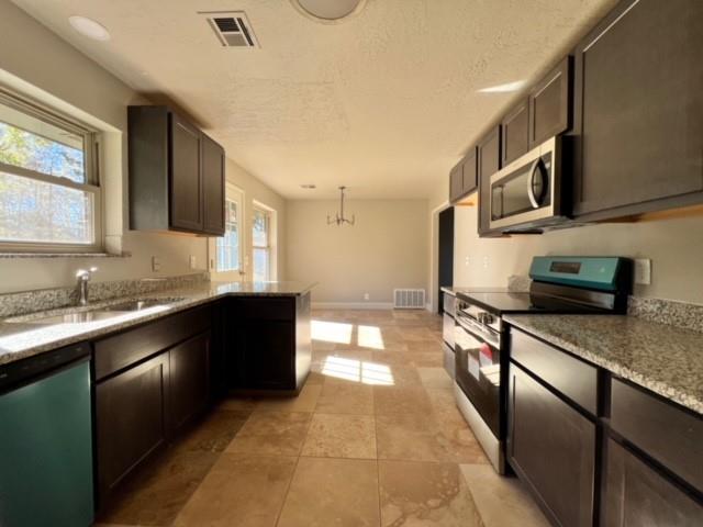 kitchen with a notable chandelier, a healthy amount of sunlight, sink, and appliances with stainless steel finishes