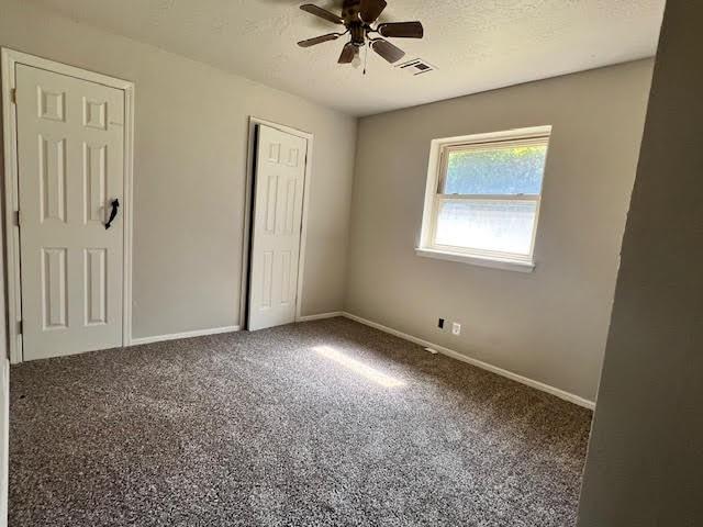 unfurnished bedroom with ceiling fan, carpet floors, and a textured ceiling