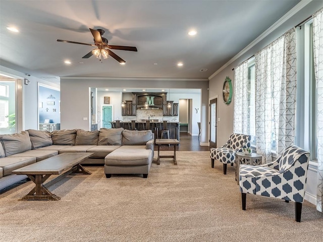 living room featuring light carpet, ceiling fan, and ornamental molding