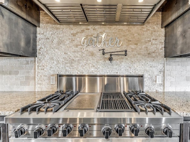 room details featuring range hood, light stone countertops, and stainless steel range