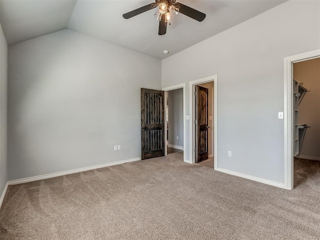 unfurnished bedroom with lofted ceiling, ceiling fan, a spacious closet, carpet floors, and a closet