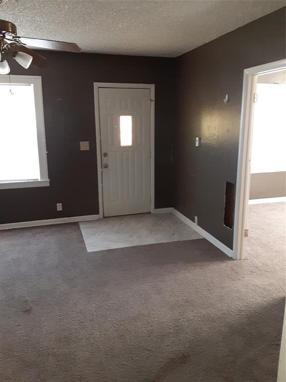 carpeted foyer with a ceiling fan, baseboards, and a textured ceiling