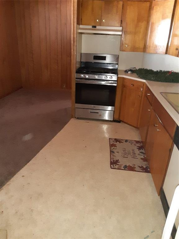 kitchen featuring stainless steel gas stove, light countertops, brown cabinets, and under cabinet range hood